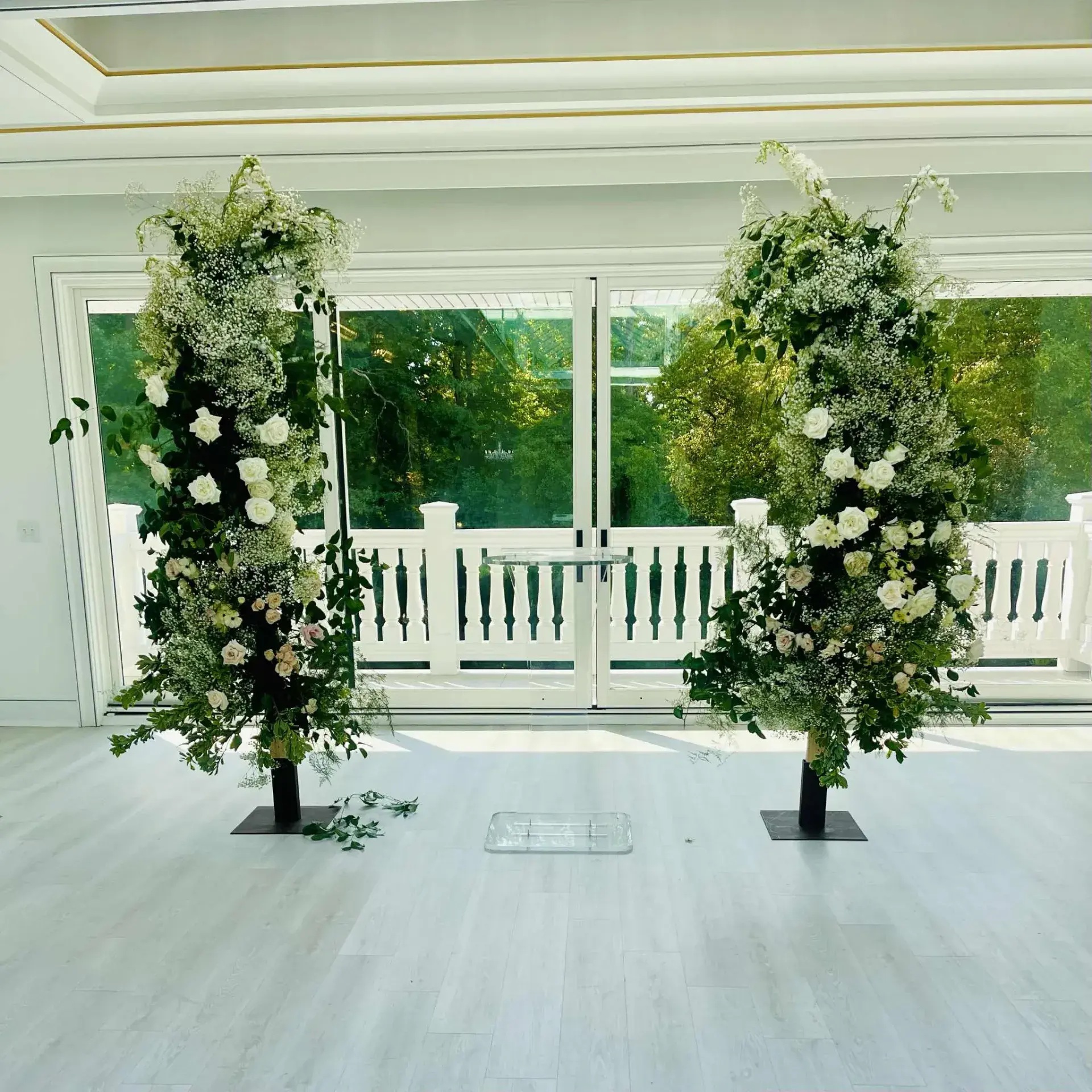 Two tall pillars of white roses, baby's breath, and greenery by Fleuristry