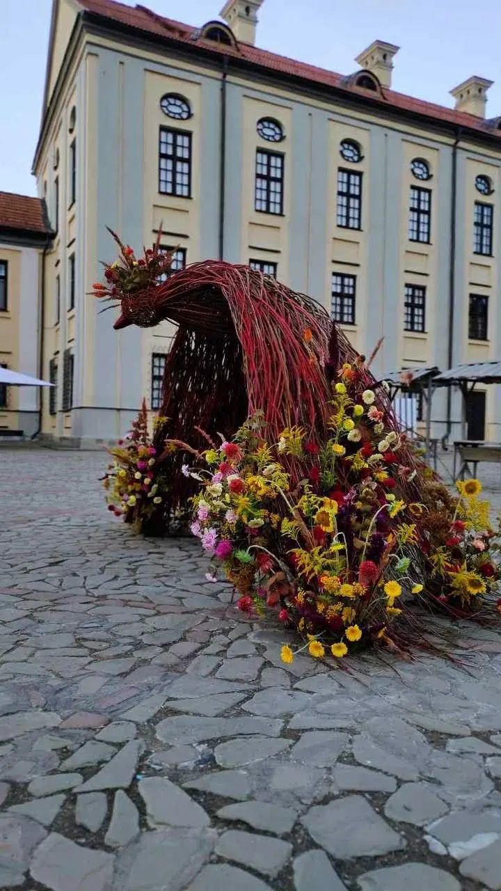 Woven bird sculpture with a tail of yellow, pink, and red flowers